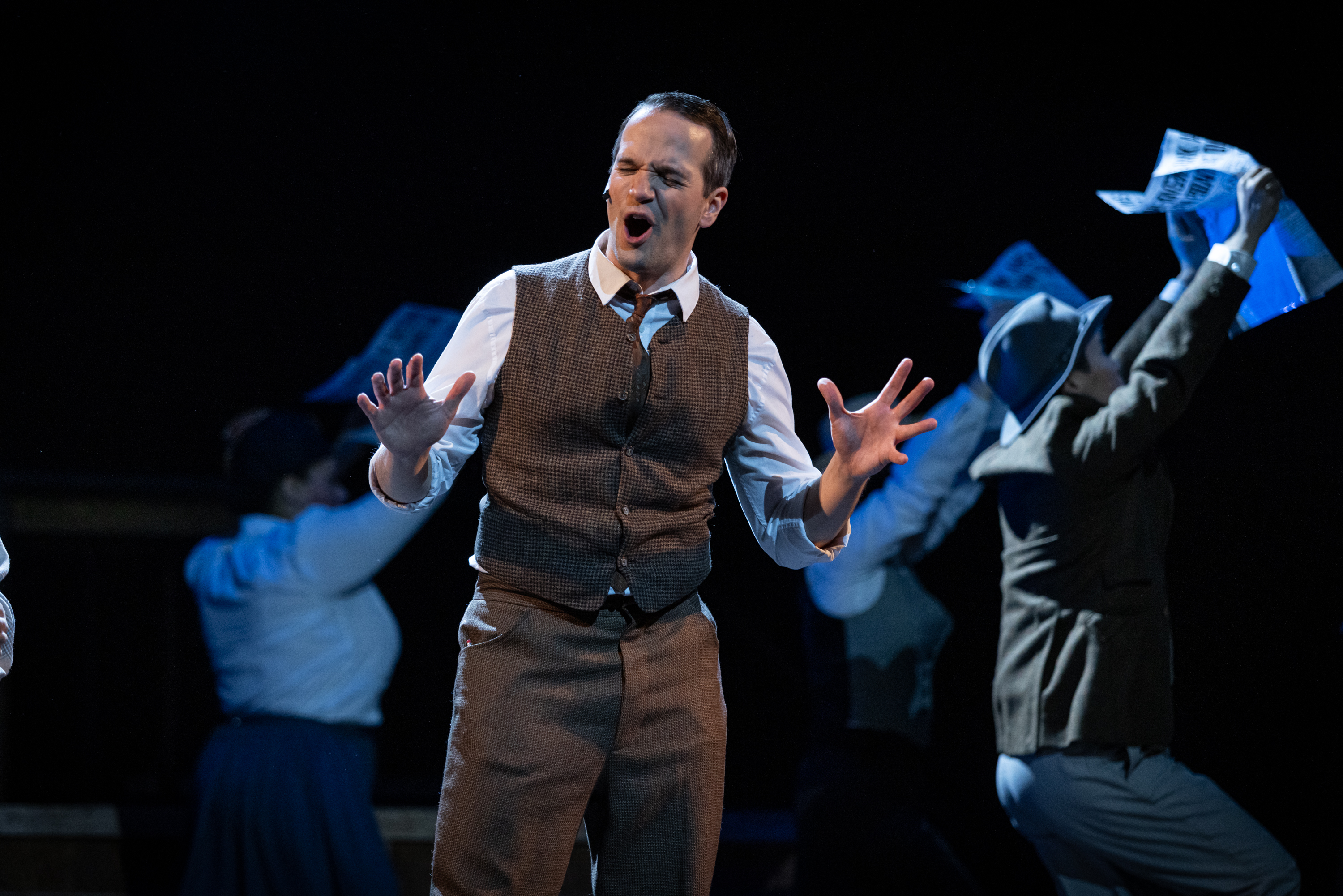 Ian Parsons performs an animated theatrical scene in a waistcoat and tie.