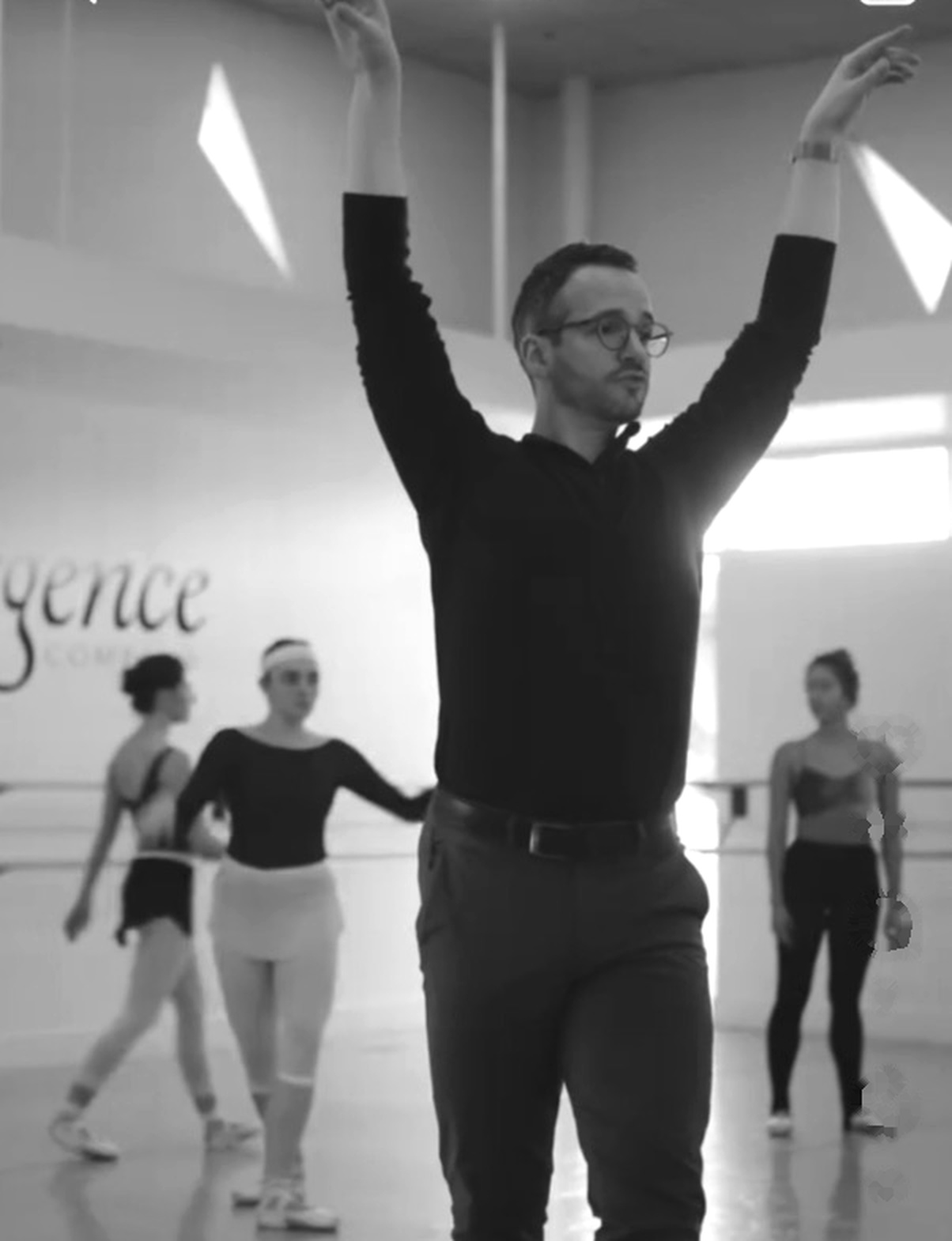 Ian Parsons demonstrates expressive port de bras while ballet students work behind him in the studio.